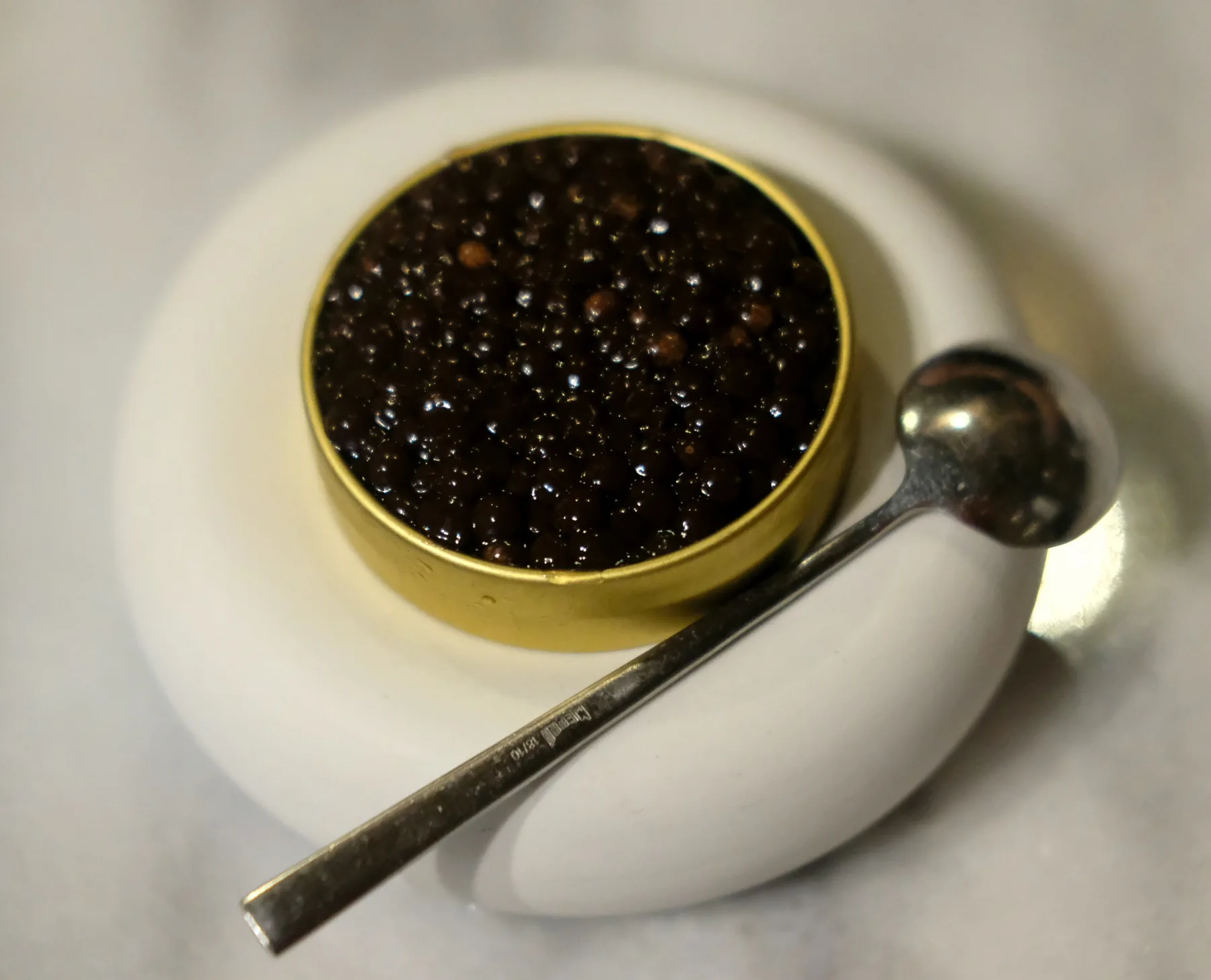 Black caviar in a gold tin with a small spoon
