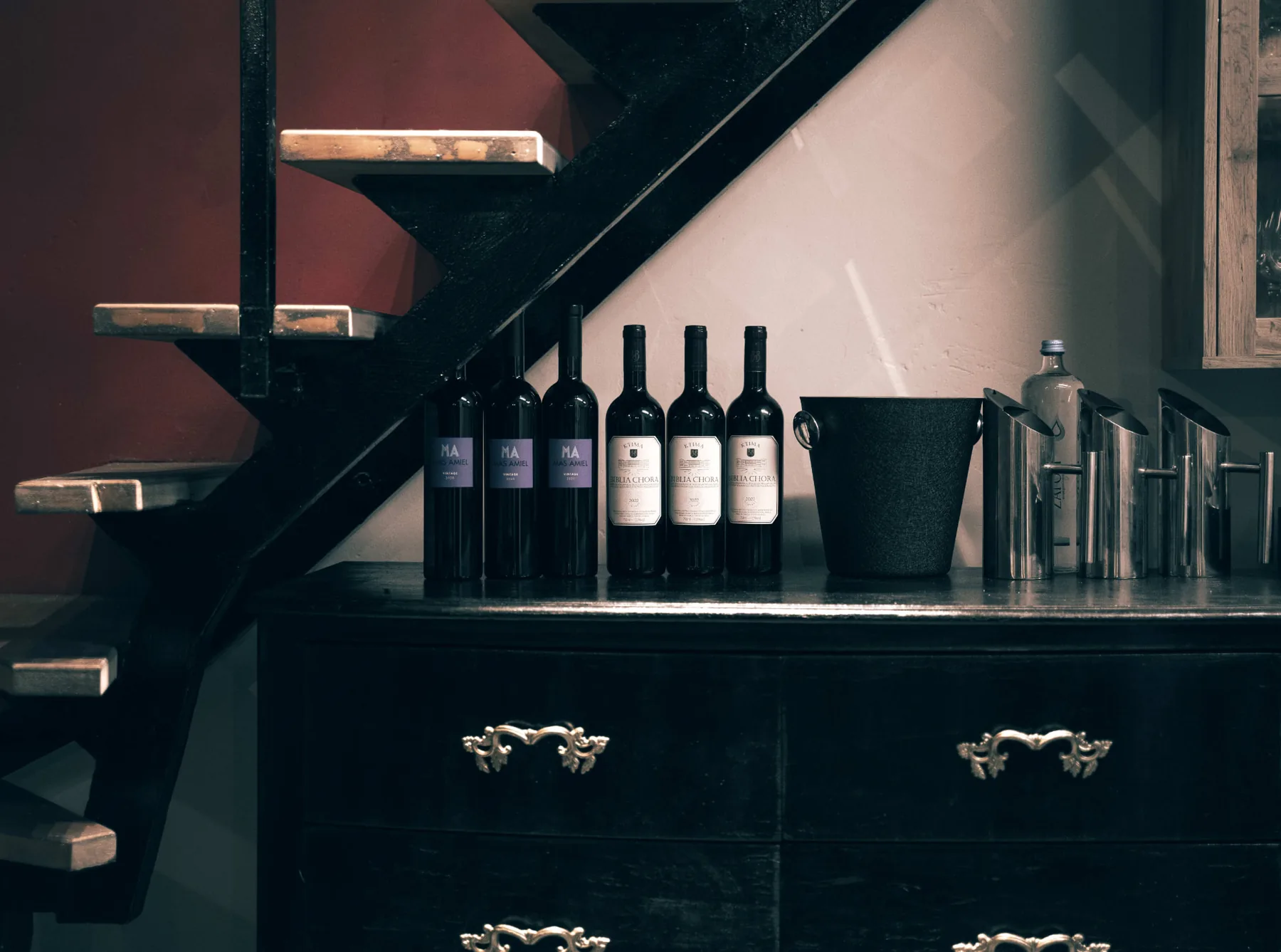 Greek wine bottles lined up beneath a spiral staircase
