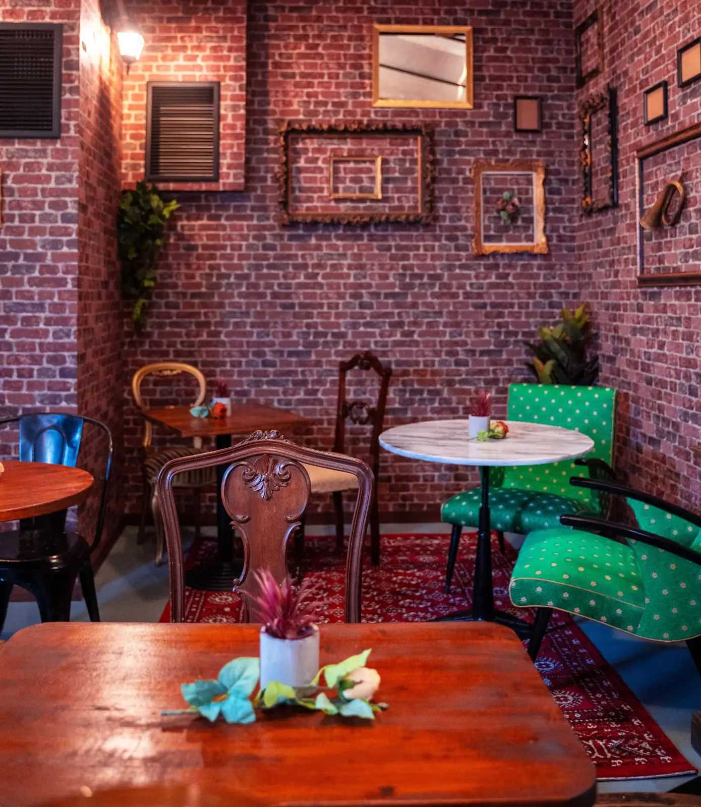 The dining room with exposed brick walls, antique frames and green polka-dot chairs